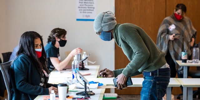 An election official assists a voter at a polling location during the Senate runoff elections in Atlanta, Georgia, U.S., on Tuesday, Jan. 5, 2021. Georgia voters are turning out in record numbers to cast ballots in two runoff elections that will determine which party controls the Senate for the next two years. Photographer: Dustin Chambers/Bloomberg via Getty Images