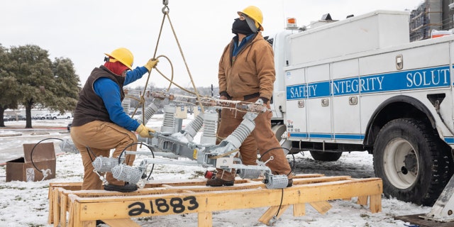 Workers repair a power line in Austin, Texas, on Feb. 18, 2021. (Thomas Ryan Allison/Bloomberg via Getty Images)