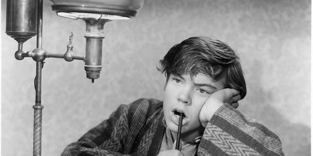 Bobby Driscoll with pen in mouth in a scene from the film 'When I Grow Up', 1951.