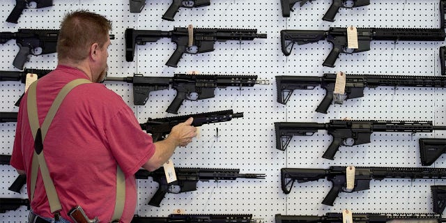 A worker restocks AR-15 guns.