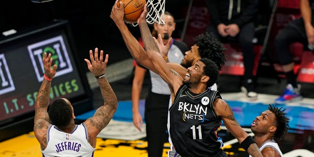 Sacramento Kings forward Marvin Bagley III tries to steal the ball from Brooklyn Nets guard Kyrie Irving (11) during the first half of an NBA basketball game, Tuesday, Feb. 23, 2021, in New York, as Sacramento Kings guards DaQuan Jeffries (19) and Buddy Hield (24) watch from the floor. (AP Photo/Kathy Willens)