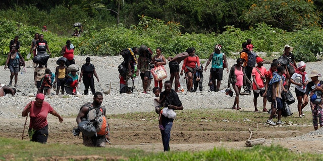 Migrants cross the Tuquesa River after a trip on foot through the jungle to Bajo Chiquito, Darien province, Panama, Wednesday, Feb. 10, 2021. Panama reopened its border in late January and ever since groups have been walking out of the dense Darien jungle that divides Panama and Colombia. (AP Photo/Arnulfo Franco)