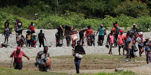 Migrants cross the Tuquesa River after a trip on foot through the jungle to Bajo Chiquito, Darien province, Panama, Wednesday, Feb. 10, 2021. Panama reopened its border in late January and ever since groups have been walking out of the dense Darien jungle that divides Panama and Colombia. (AP Photo/Arnulfo Franco)