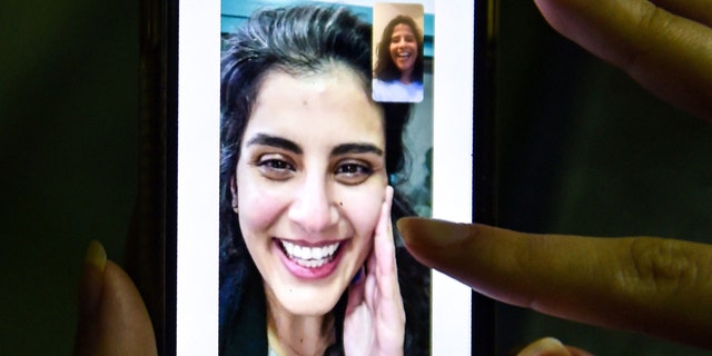 This picture taken February 10, 2021 in Saudi Arabia's capital Riyadh shows a woman viewing a tweet posted by the sister of Saudi activist Loujain al-Hathloul, Lina, showing a screenshot of them having a video call following Hathloul's release after nearly three years in detention. (Photo by Fayez Nureldine / AFP) (Photo by FAYEZ NURELDINE/AFP via Getty Images)