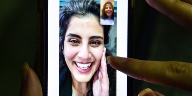 This picture taken February 10, 2021 in Saudi Arabia's capital Riyadh shows a woman viewing a tweet posted by the sister of Saudi activist Loujain al-Hathloul, Lina, showing a screenshot of them having a video call following Hathloul's release after nearly three years in detention. (Photo by Fayez Nureldine / AFP) (Photo by FAYEZ NURELDINE/AFP via Getty Images)