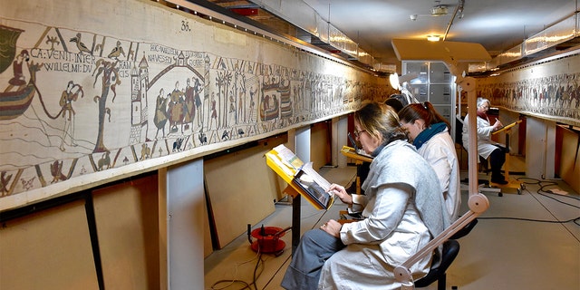 This photo provided by Bayeux townhall shows technicians working at the tapestry in Bayeux, Normandy on Jan. 8 2020. (Ville de Bayeux via AP)