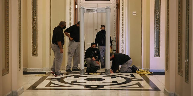 WASHINGTON, DC - JANUARY 12: U.S. Capitol Police install a metal detector outside the House of Representatives Chamber, on the very spot where less than a week earlier violent insurrectionists attempted to smash their way through and halt the certification of the Electoral College votes, January 12, 2021 in Washington, DC. At the direction of President Donald Trump, the mob attacked the U.S. Capitol on January 6 and security has been tightened ahead of next week’s presidential inauguration. (Photo by Chip Somodevilla/Getty Images)