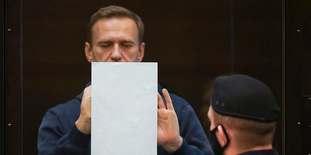 Navalny holds a document standing in the cage during a hearing Tuesday, Feb. 2, 2021. (Moscow City Court via AP)