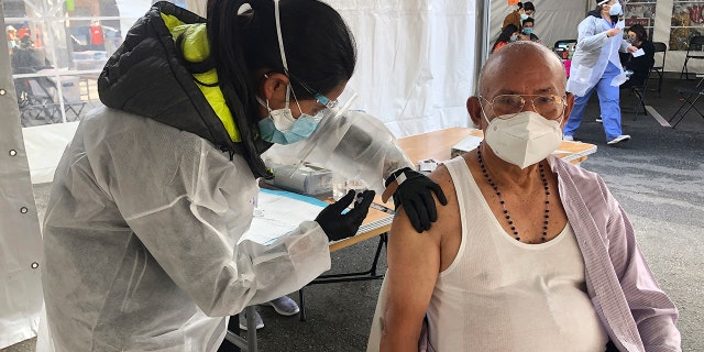 Victor Villegas, 78, right, receives a COVID-19 vaccine shot from a health care worker at a vaccination site in the Mission district of San Francisco, Monday, Feb. 8, 2021.