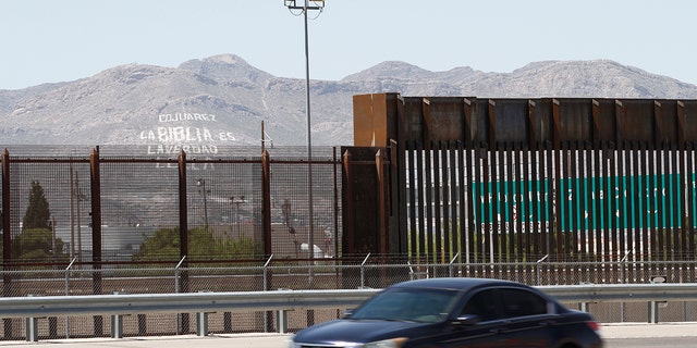 FILE - In this April 22, 2020, photo, a car drives on a highway parallel to a border fence in El Paso, Texas. (AP Photo/Cedar Attanasio, File)