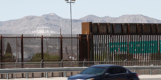 FILE - In this April 22, 2020, photo, a car drives on a highway parallel to a border fence in El Paso, Texas. (AP Photo/Cedar Attanasio, File)