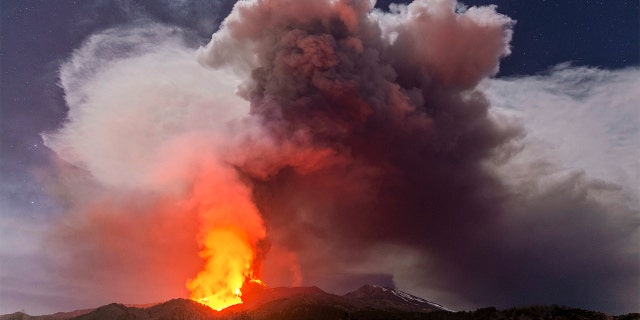 Glowing lava is seen from the north-east side of the Mt Etna volcano engulfed with ashes and smoke near Milo, Sicily, Wednesday night, Feb. 24, 2021.  (AP Photo/Salvatore Allegra)