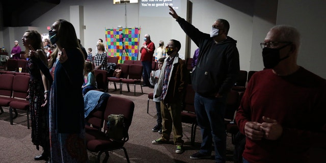 Travis Lowe, second from right, pastor of Crossroads Church in Bluefield, W.Va., raises his arm during services Sunday Jan. 23, 2021. Lowe, who has expressed concern over the divisiveness of American politics, believes collaboration by churches will help heal his town and the country. (AP Photo/Jessie Wardarski)
