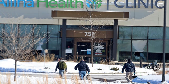 Law enforcement personnel walk toward the Allina Health clinic on Tuesday following the shooting there. (AP/Star Tribune)