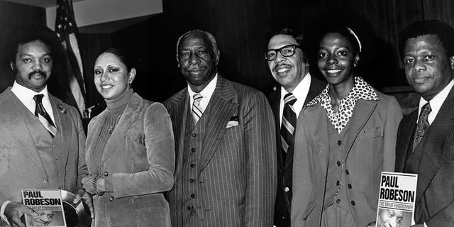 Jesse Jackson and others pose with copies of "Paul Robeson, the Great Forerunner" by the editors of Freedomways, 1980.