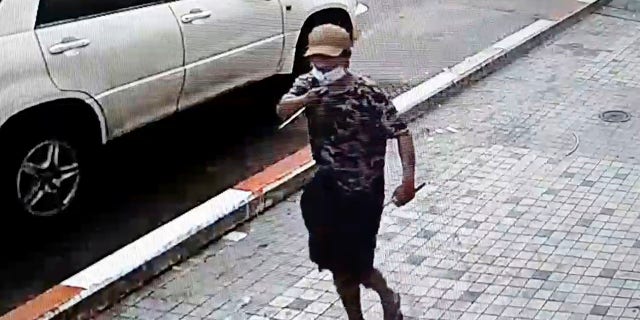 In this image taken from video obtained by Than Lwin Khet News, a man holds a pointed instrument before he attacks an unidentified man on the sidewalk of Sule Pagoda Road in Yangon, Burma, on Thursday. (Than Lwin Thet News via AP)