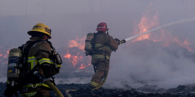 Firefighters battle a fire at a commercial yard in Compton, Calif., on Feb. 26, 2021. (AP Photo/Ringo H.W. Chiu)