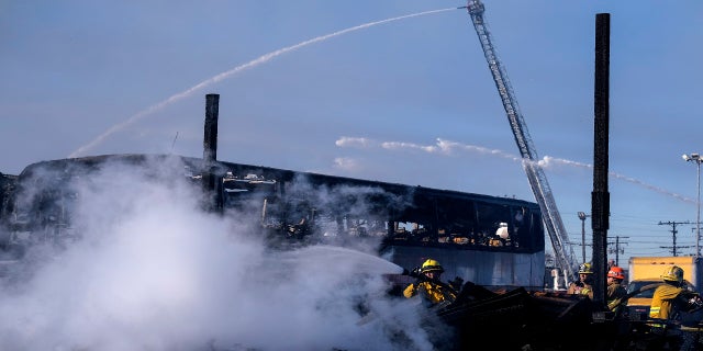 Firefighters battle a fire at a commercial yard in Compton, Calif. on Feb. 26, 2021. (AP Photo/Ringo H.W. Chiu)