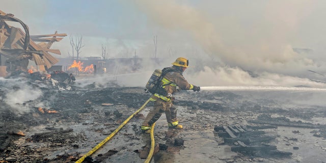 A firefighter battles a fire at at commercial yard in Compton, Calif., on Feb. 26, 2021. (AP Photo/Ringo H.W. Chiu)