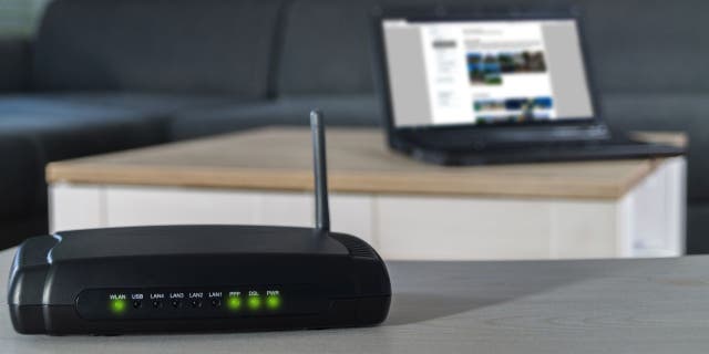 Internet connection at home. Wifi router on the desk with a notebook in the background.