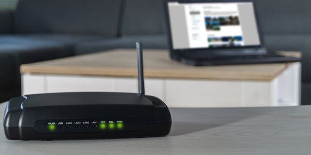 Home internet connection. A wlan router on desk with notebook in background.