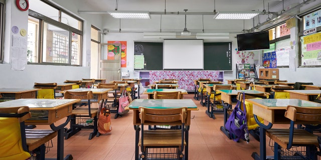 Row of empty desks in front of whiteboard. Interior of classroom in school.