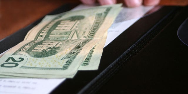 Money and receipt being placed on the payment binder for payment of a meal.