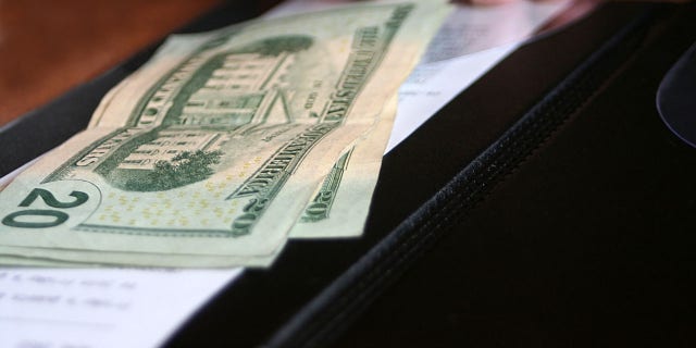 Money and receipt being placed on the payment binder for payment of a meal.