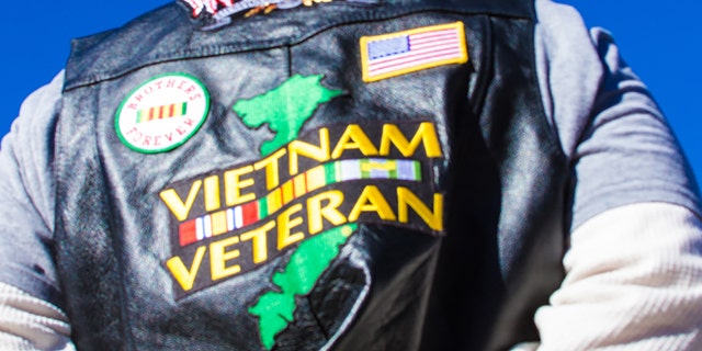 Santa Fe, USA - November 11, 2010: A Vietnam veteran holds a US flag at a Veteran's Day memorial in Santa Fe, NM, backdropped by a deep blue sky.