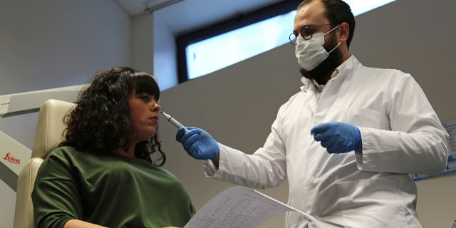Feb. 8, 2021: Dr. Clair Vandersteen, right, wafts a tube of odors under the nose of a patient, Gabriella Forgione, during tests in a hospital in Nice, southern France, to help determine why she has been unable to smell or taste since she contracted COVID-19 in November 2020.