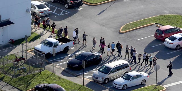 Students are evacuated by police from Marjory Stoneman Douglas High School in Parkland, Fla., during the shooting that took place there in February. (AP/South Florida Sun-Sentinel)