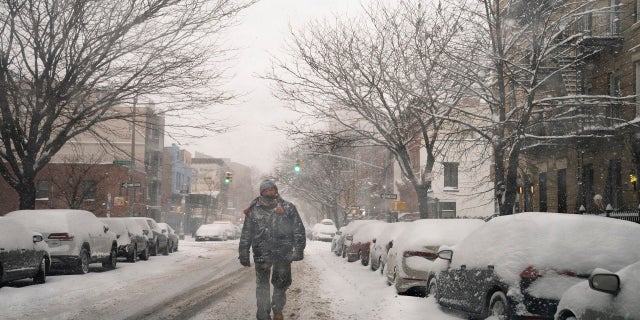 A pedestrian walks down a snow covered street in the Brooklyn borough of New York City on Monday. (AP)
