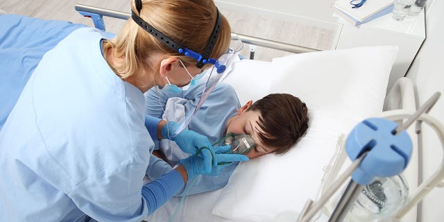 A nurse takes care of a child in a hospital bed. Many health experts believe the surge in RSV cases may be related to COVID-19 mitigation efforts.