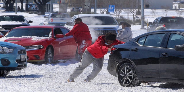 People push a car free after spinning out in the snow Monday in Waco, Texas. (AP/Waco Tribune-Herald)