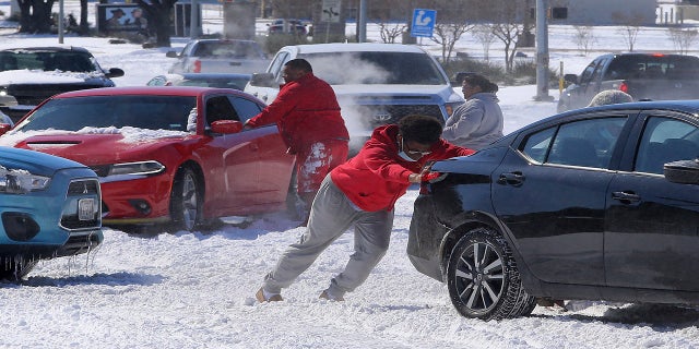 People push a car free after spinning out in the snow Monday in Waco, Texas. (AP/Waco Tribune-Herald)