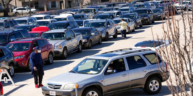 Hundreds of cars are staged in a parking lot in line at a food and water distribution site on Monday in Houston. (AP)