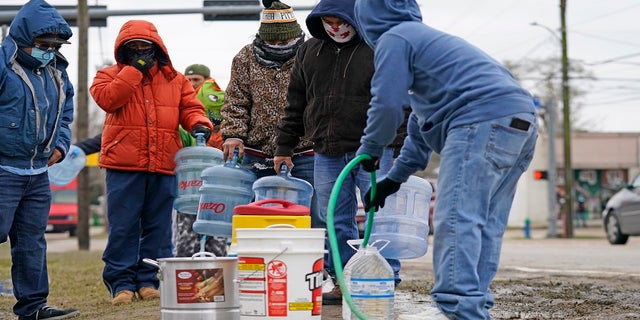 Jose Blanco, right, fills a cooler with water from a park spigot as others wait in line Thursday in Houston. Houston and several surrounding cities are under a boil water notice as many residents are still without running water in their homes. (AP)