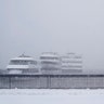 A man walks along a waterfront that usually has a view of the New York City skyline in Hoboken, N.J., Monday, Feb. 1, 2021. A sprawling, lumbering winter storm is walloping the Eastern U.S., shutting down coronavirus vaccination sites, closing schools and halting transit. (AP Photo/Seth Wenig)