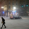 A woman crosses Wooster Street as snow falls Monday, Feb. 15, 2021, in downtown Bowling Green, Ohio. Much of the area is expected to receive a foot of snow.