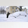 A man brushes snow off his car, Tuesday, Feb. 2, 2021, in Lawrence, Mass. A sprawling, lumbering winter storm has walloped the Eastern U.S., shutting down coronavirus vaccination sites, closing schools and halting transit.