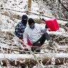 Two men climb over downed trees as they head out to retrieve gas for generators, Tuesday, Feb. 16, 2021, in Huntington, W.Va., following a winter weather system.