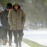 Erasmo Vazquez, right, walks along a snow- covered sidewalk with his wife, Maria, center, and daughter Day, left, Monday, Feb. 15, 2021, in Houston. A winter storm dropping snow and ice sent temperatures plunging across the southern Plains, prompting a power emergency in Texas a day after conditions canceled flights and impacted traffic across large swaths of the U.S.