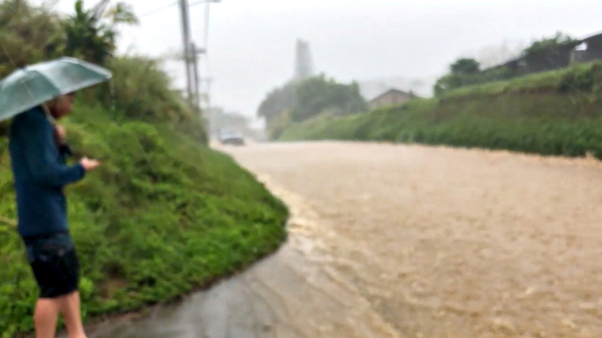 People look at a flooded street near the breached Kaupakalua dam, in Haiku on Maui, Hawaii, U.S. March 8, 2021, in this still image from a social media video. WWW.MONKEYSWITHDRUMS.COM via REUTERS