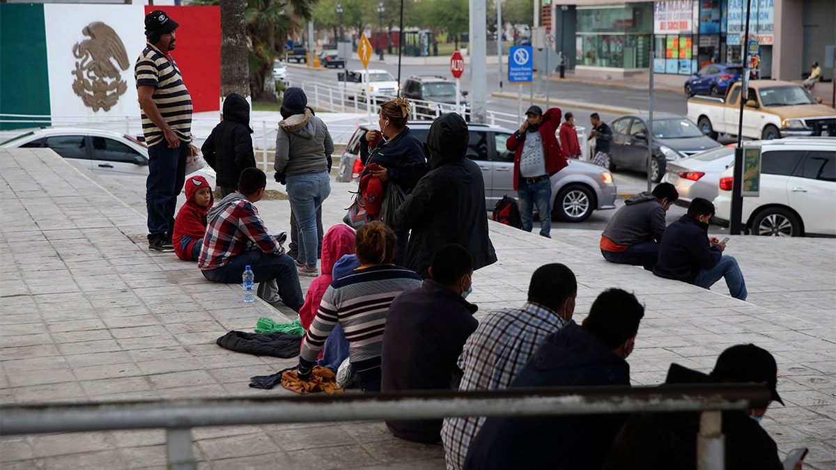 Migrants recently expelled from the U.S. after trying to seek asylum sit next to the international bridge in the Mexican border city of Reynosa, Saturday, March 27, 2021. (AP Photo/Dario Lopez-Mills)