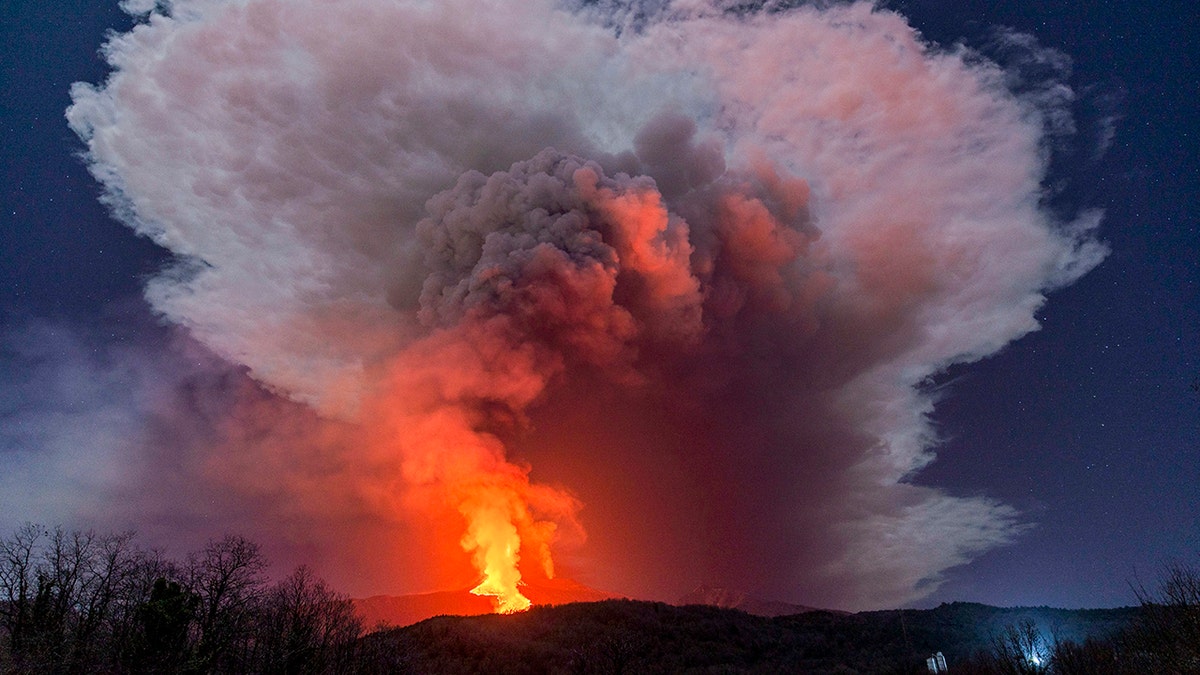 FILE - In this Wednesday, Feb. 24, 2021 file photo, a fiery river of glowing lava flows on the north-east side of the Mt. Etna volcano engulfed with ashes and smoke near Milo, Sicily. (AP Photo/Salvatore Allegra, File )