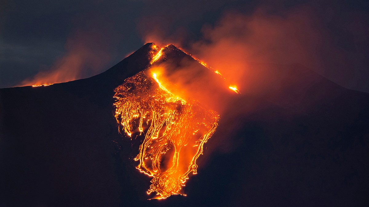 The moon is partially seen in the sky as lava flows from the Mt. Etna volcano, near Catania in Sicily, southern Italy, early Tuesday, Feb. 23 , 2021. (AP Photo/Salvatore Allegra)