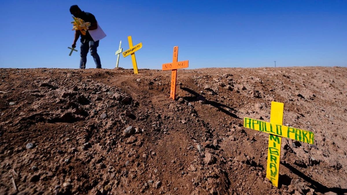 Hugo Castro leaves crosses at the scene of a deadly crash in Holtville, Calif., Tuesday, March 2, 2021. Authorities say a semitruck crashed into an SUV, killing multiple people. (AP Photo/Gregory Bull)