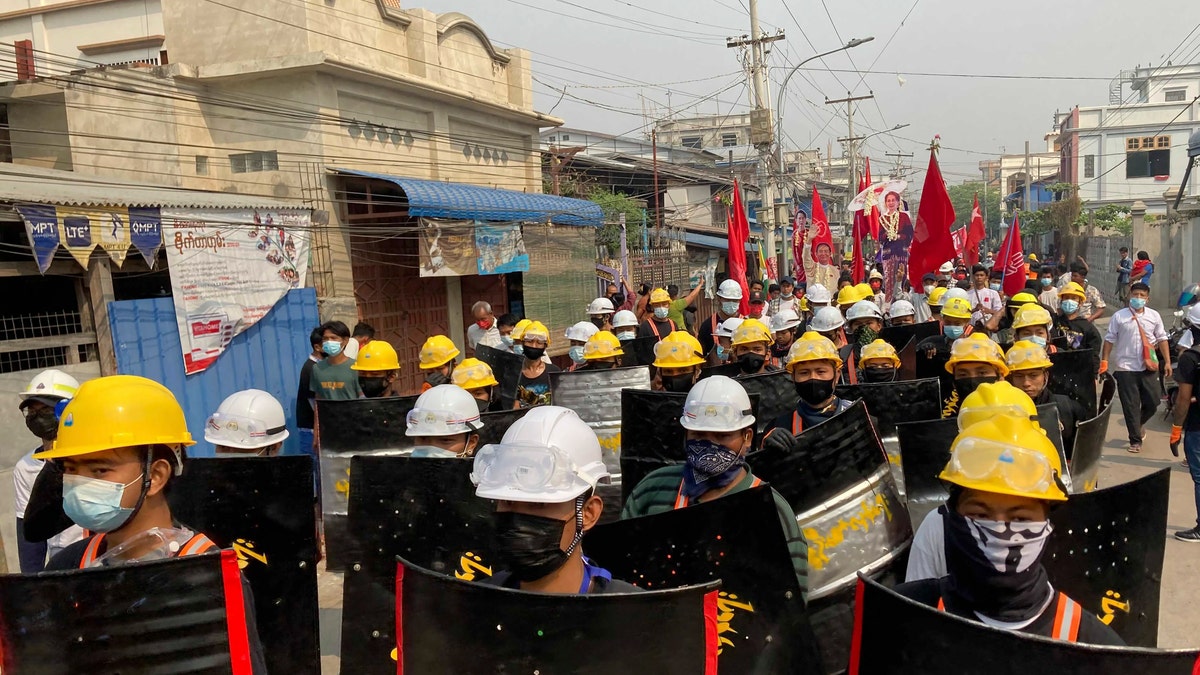 Protesters march with makeshift shields on a main road during a demonstration in Mandalay, Burma, Monday, March 8, 2021. Large protests have occurred daily across many cities and towns in Burma. (AP Photo)