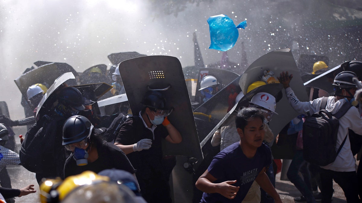 Protesters are dispersed as riot police fire tear gas during a demonstration in Yangon, Burma, Monday, March 8, 2021. (AP Photo)