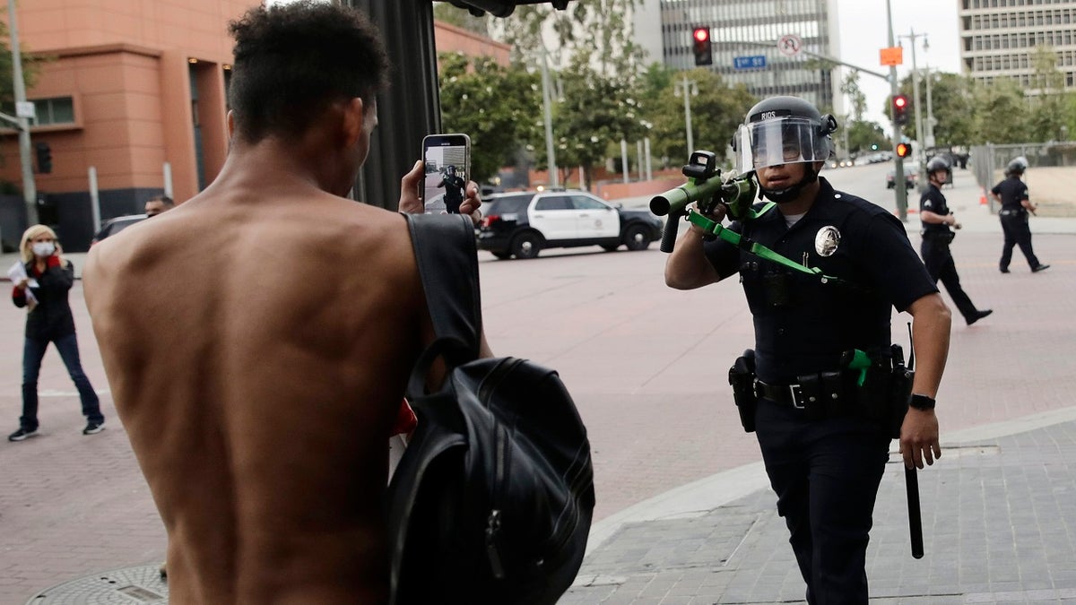 FILE - In this June 2, 2020, file photo, a police officer aims his less-lethal weapon at a demonstrator during a protest in Los Angeles, over the death of George Floyd on May 25 while in police custody in Minneapolis. (AP Photo/Jae C. Hong, File)